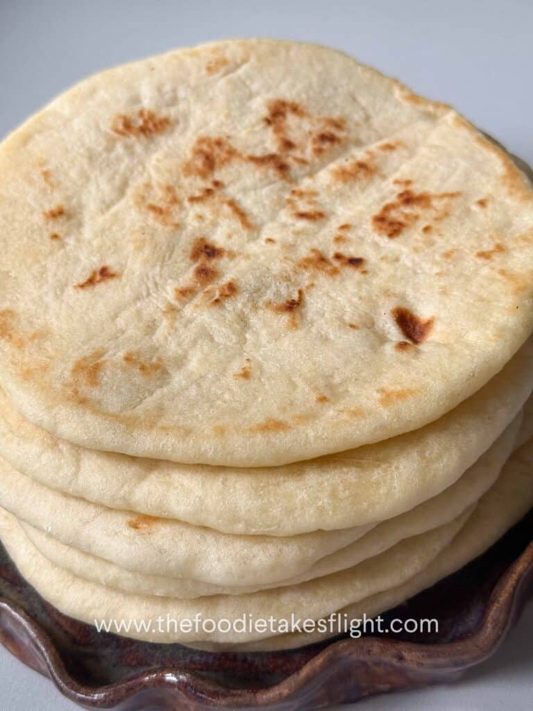 Easy homemade pita bread stacked on a plate with soft, fluffy texture and golden brown spots