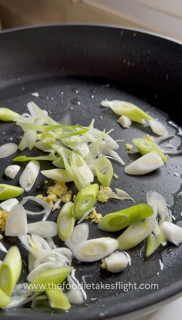 White parts of scallions, minced ginger stir-frying in a hot pan