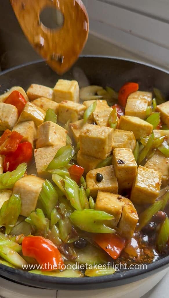 Sauce poured over tofu, celery, and bell pepper in the pan