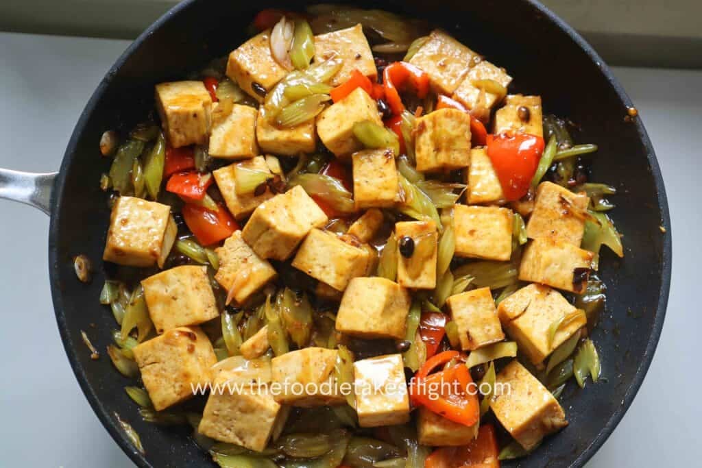 Stir-fried tofu and celery cooking until the sauce thickens and coats everything