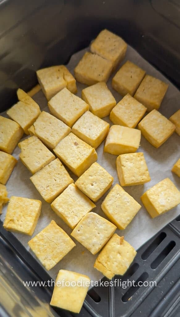 Golden pieces of tofu cubes laid out on an air fryer