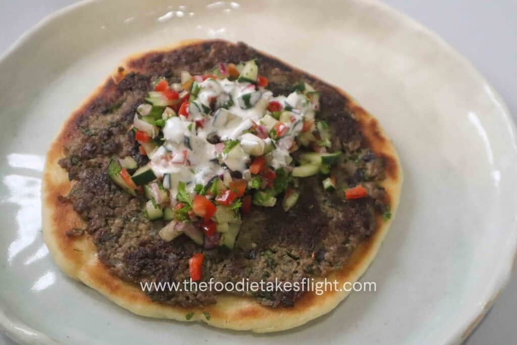 Greek-style smashed kebab pitas topped with chopped cucumber salad, parsley, and creamy yogurt dressing