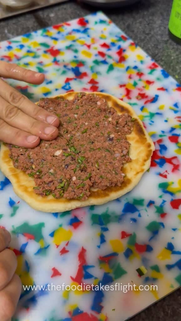 Seasoned Impossible meat spread onto the open side of pita bread before cooking