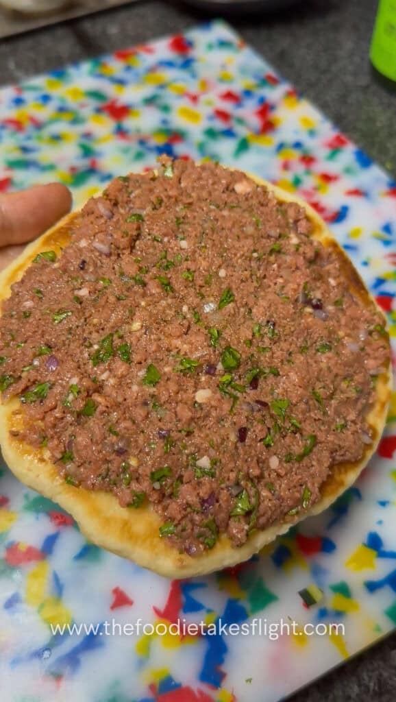 Seasoned Impossible meat spread onto the open side of pita bread before cooking