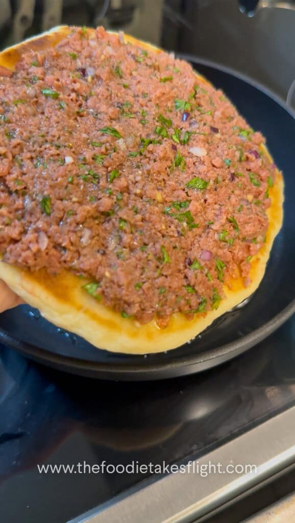 Seasoned Impossible meat spread onto the open side of pita bread before cooking