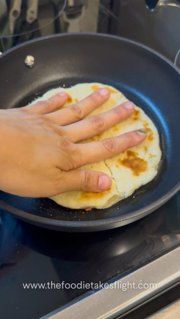 Seasoned Impossible meat spread onto the open side of pita bread before cooking