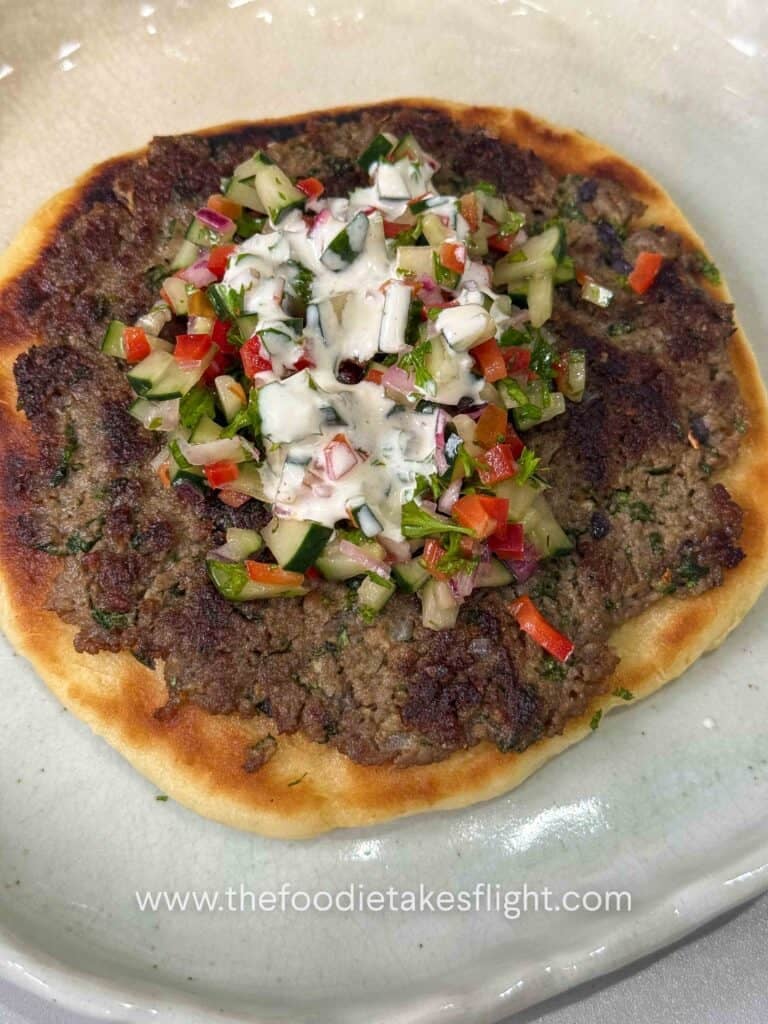 Greek-style smashed kebab pitas topped with chopped cucumber salad, parsley, and creamy yogurt dressing
