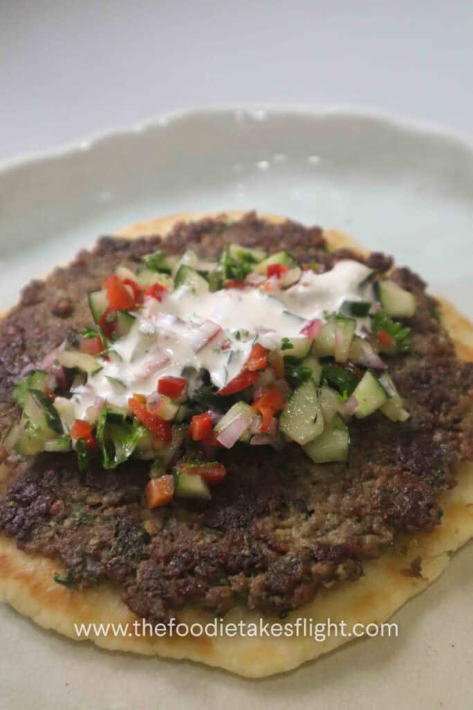 Greek-style smashed kebab pitas topped with chopped cucumber salad, parsley, and creamy yogurt dressing