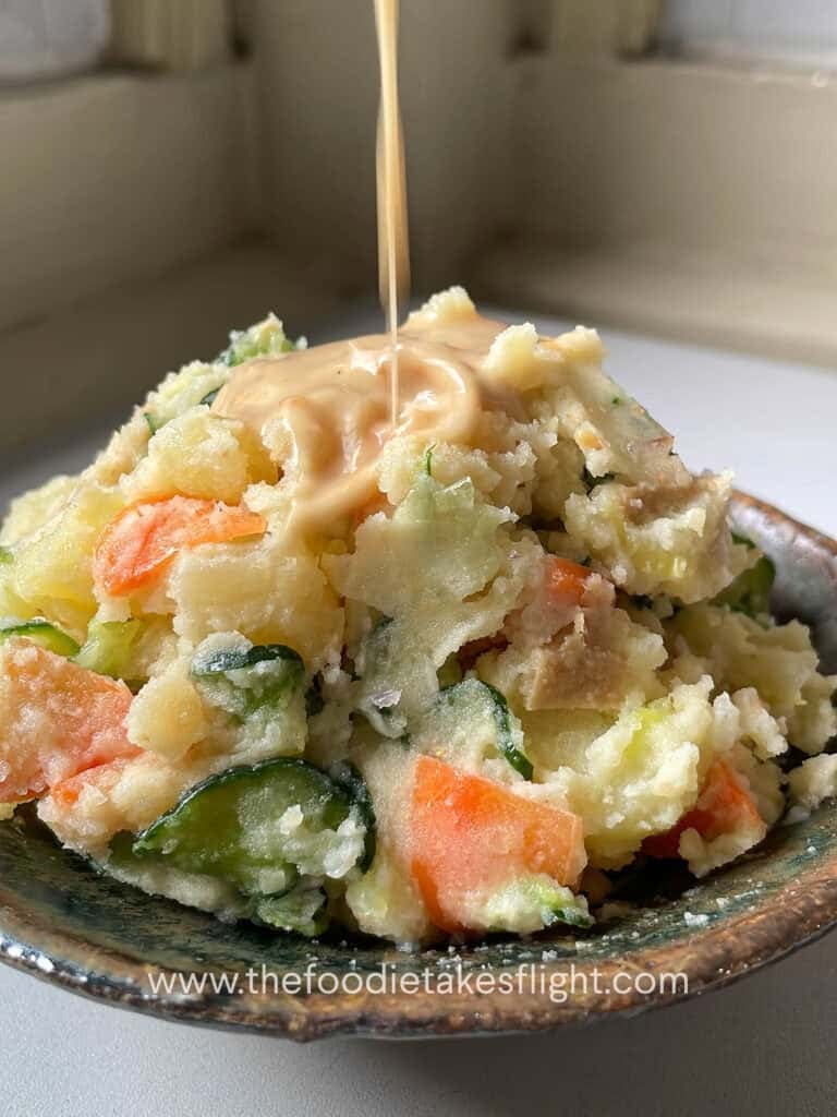 adding roasted sesame dressing to Japanese potato salad with cucumber, carrot, vegan ham, scallions, and roasted sesame dressing