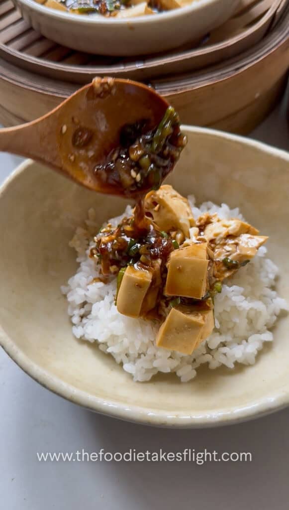 pouring ginger scallion sauce over the rice and tofu