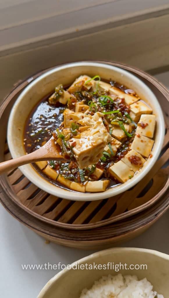 scooping steamed silken tofu with ginger scallion sauce