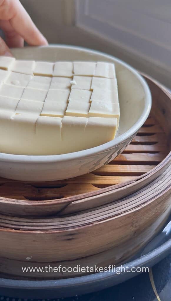 Silken tofu in a bowl set inside a steamer basket before steaming