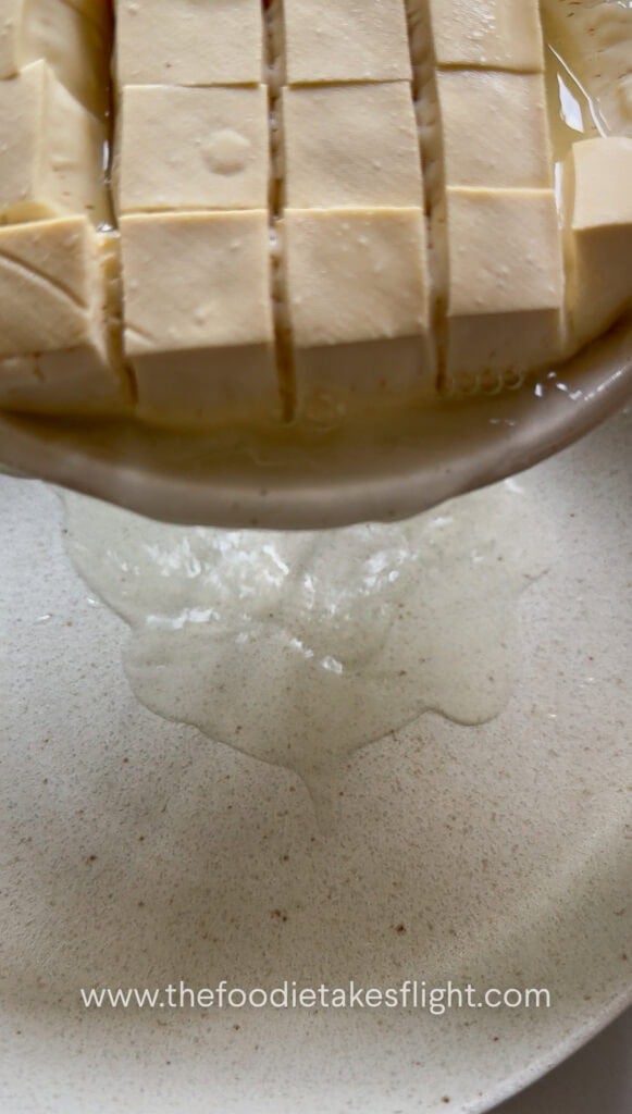Draining water from steamed silken tofu after releasing excess liquid