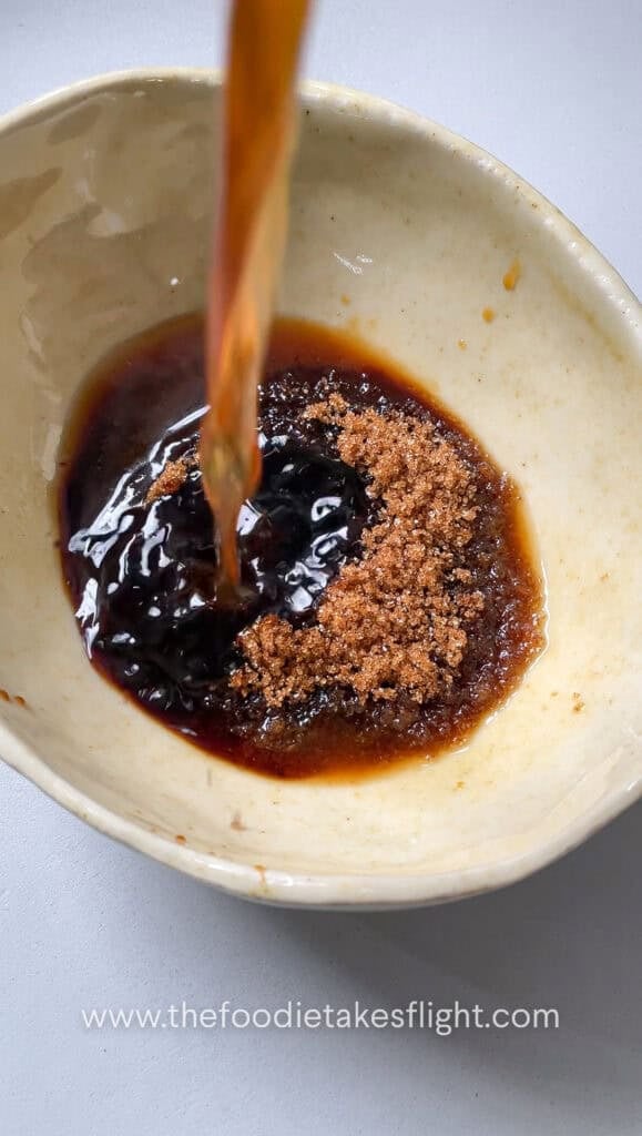Soy sauce, hoisin sauce, brown sugar, dark soy sauce, Chinese five spice, Shaoxing wine, white pepper, chili oil, and water mixed in a bowl