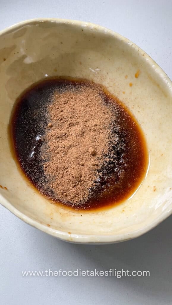 Soy sauce, hoisin sauce, brown sugar, dark soy sauce, Chinese five spice, Shaoxing wine, white pepper, chili oil, and water mixed in a bowl