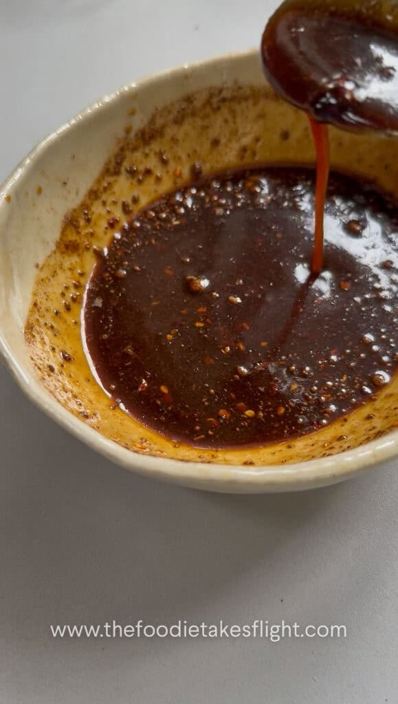 Soy sauce, hoisin sauce, brown sugar, dark soy sauce, Chinese five spice, Shaoxing wine, white pepper, chili oil, and water mixed in a bowl