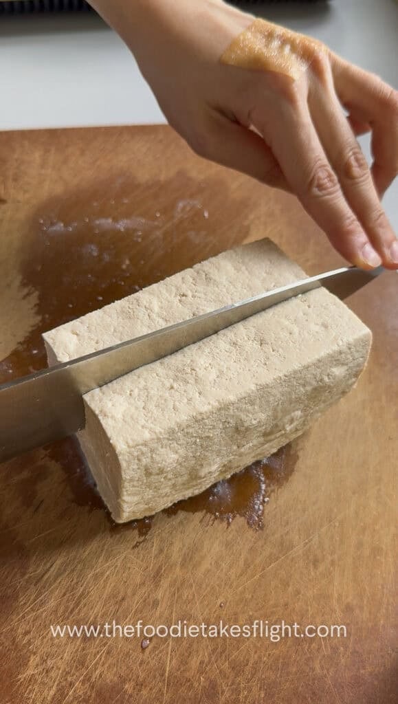a block of extra firm tofu on a wooden cutting board