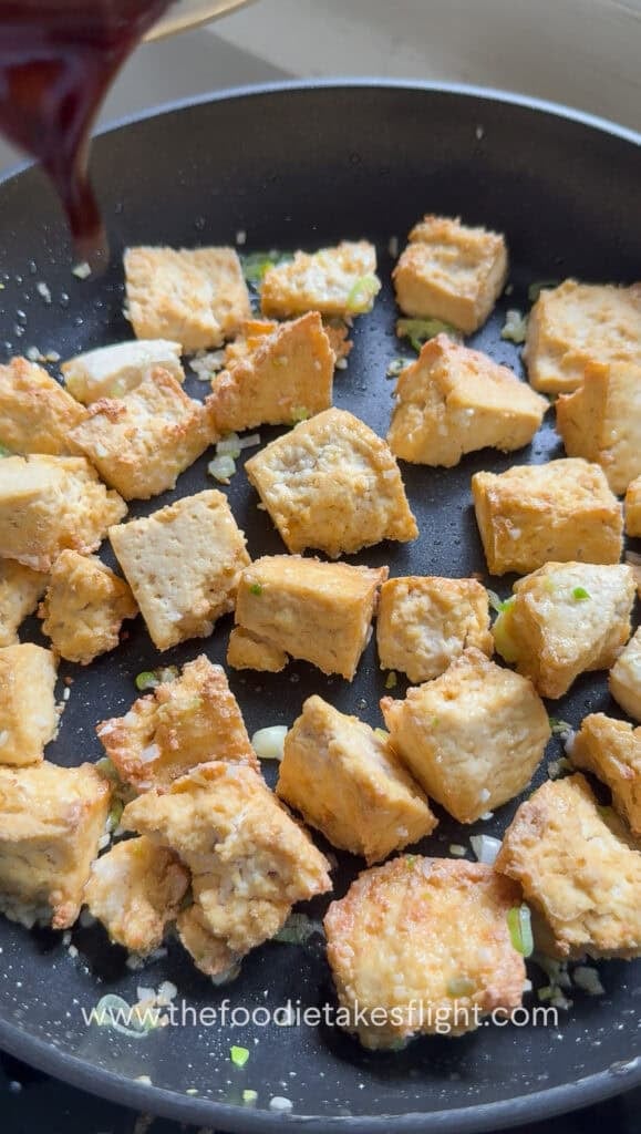 Crispy tofu added to the pan with garlic and scallions