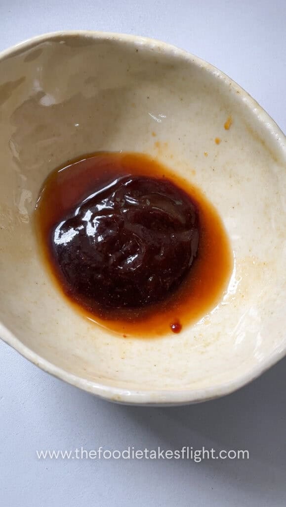 Soy sauce, hoisin sauce, brown sugar, dark soy sauce, Chinese five spice, Shaoxing wine, white pepper, chili oil, and water mixed in a bowl