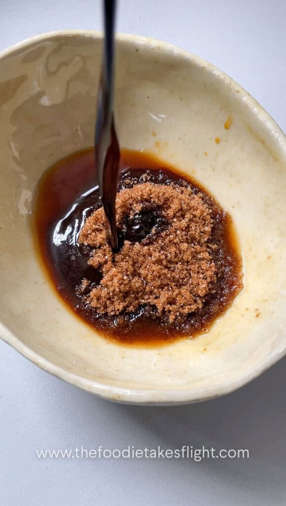 Soy sauce, hoisin sauce, brown sugar, dark soy sauce, Chinese five spice, Shaoxing wine, white pepper, chili oil, and water mixed in a bowl