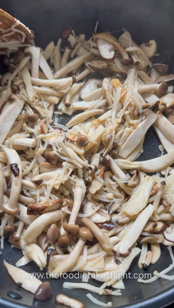 Mushrooms cooking in a dry wok until they release moisture