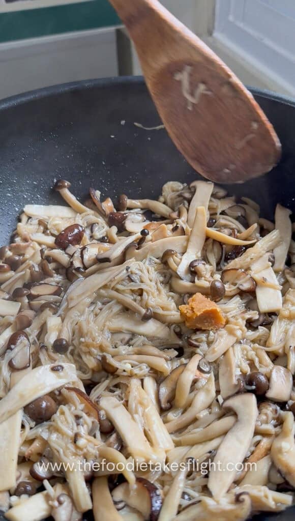 Miso seasoning poured over seared mushrooms in the wok