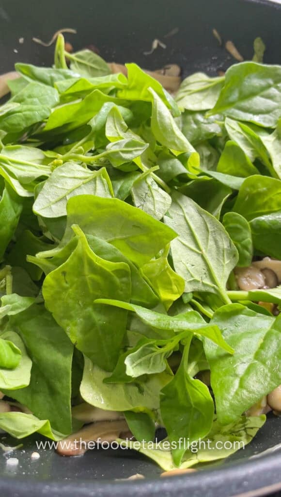 Spinach leaves added to cooked mushrooms after turning off the heat