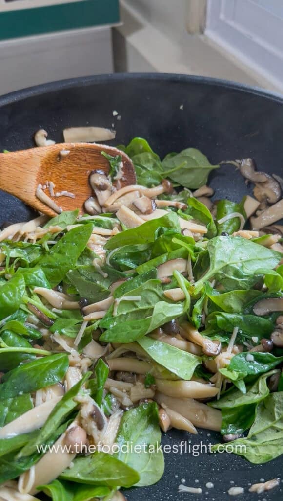 Spinach leaves added to cooked mushrooms after turning off the heat