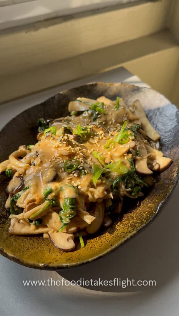 Warm mushroom salad topped with chopped scallions and roasted sesame seeds