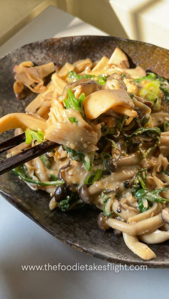Warm mushroom salad topped with chopped scallions and roasted sesame seeds