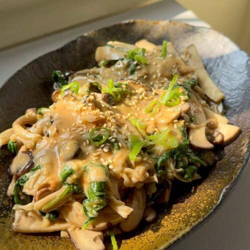 Warm mushroom salad topped with chopped scallions and roasted sesame seeds