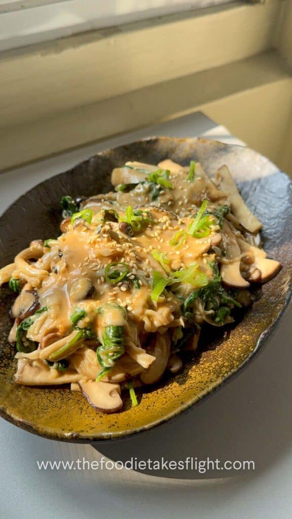 Warm mushroom salad topped with chopped scallions and roasted sesame seeds