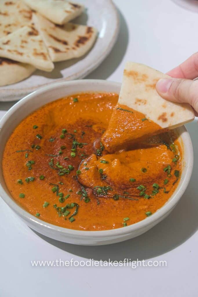 Roasted red pepper dip garnished with smoked paprika, chopped chives, and thinly sliced mint